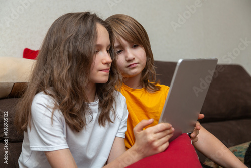 Young girls using a tablet on the sofa at home