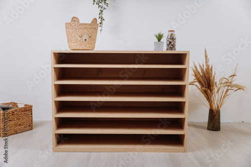 Wooden multi tier shelf cabinet in modern playroom interior, front view