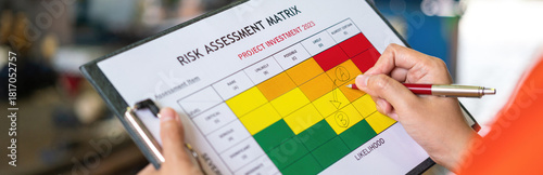 Photos Close-up at supervisor hand is using pen to checking on project risk assessment form to evaluate serverity level