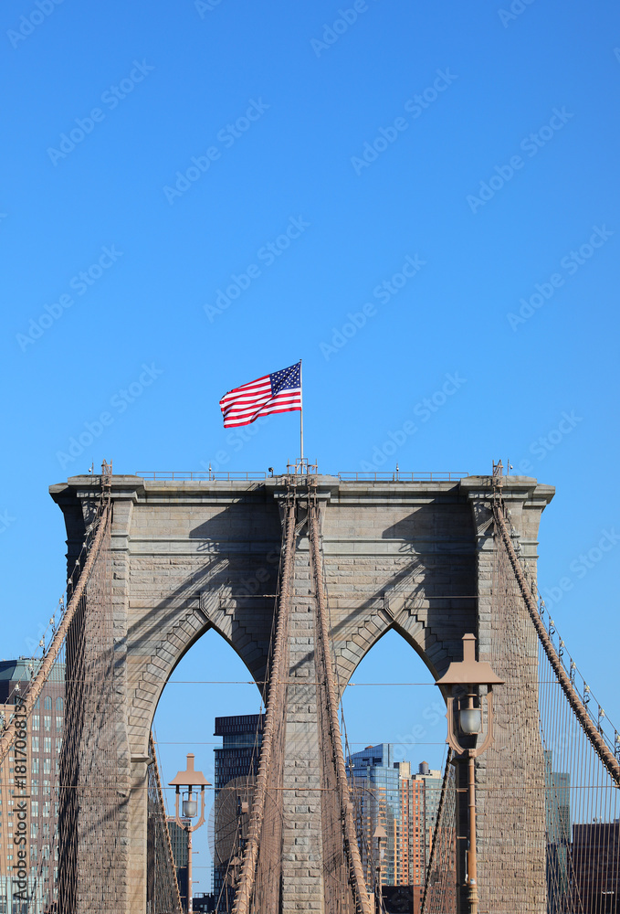 Fototapeta premium waving american flag on the brooklyn bridge tower in new york usa