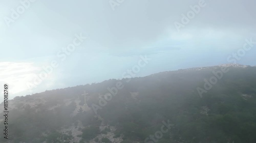 Panoramic view of the stunning Croatian Adriatic coastline from a mountain peak, with islands dotting the cloudy horizon and a charming coastal town below.