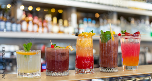 Canvas Print Five vibrant, colorful cocktails lined up on a sleek bar counter, each garnished with fresh fruit, mint, and citrus twists