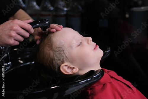 Young boy relaxing during hair washing in barbershop