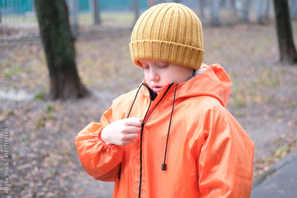 Wall Mural Child zipping rain jacket in park outdoors