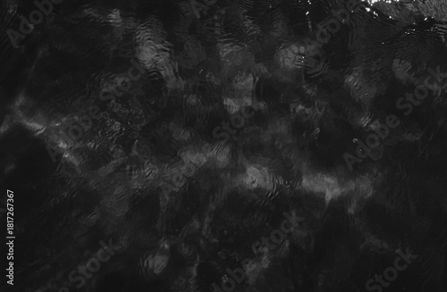 Photography Abstract background of dark, rippling water with grey reflections creating a dynamic, textured pattern