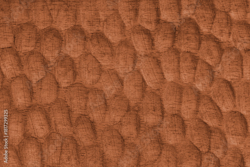 Textured orange wooden surface with carved oval patterns and visible wood grain. Abstract texture background ideal for design, craft, or natural texture themes.