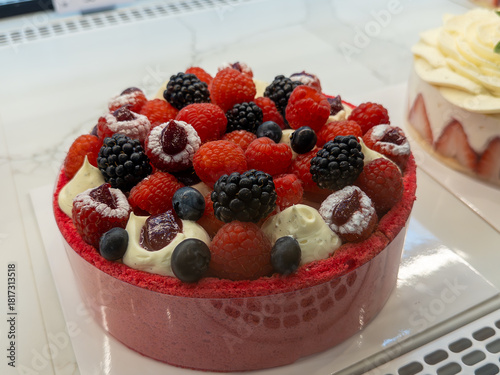 Delightful berry cake adorned with fresh fruits at a pastry shop display