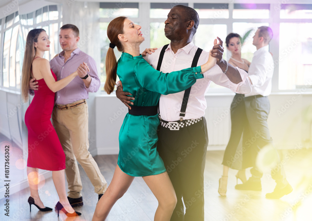 Naklejka premium Dynamic middle-aged male and female attendees of dancing courses doing waltz in group