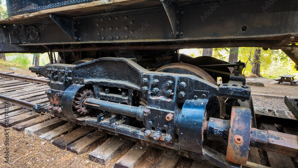 Naklejka premium Sierra Nevada Logging Museum looking a a vintage steam locomotive used to move timber from the mountains tho the sawmills showing the undercarriage of the engine