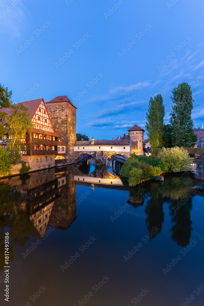 Fototapeta premium Old Town at Evening Twilight. Weinstadel Building, Henkerbrucke Bridge and Henkerturm Tower. Pegnitz River. Reflection in Water. Nuremberg, Franconia, Germany. Wide Shot