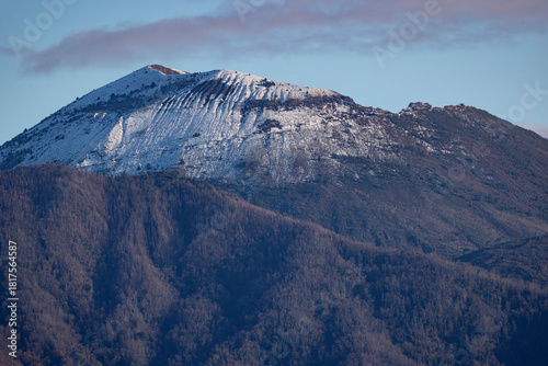 Close-up view of Mount Vesuvius covered in fresh snow. The volcanic ridges are visible under the white layer, creating a strong contrast with the dark forested slopes below.