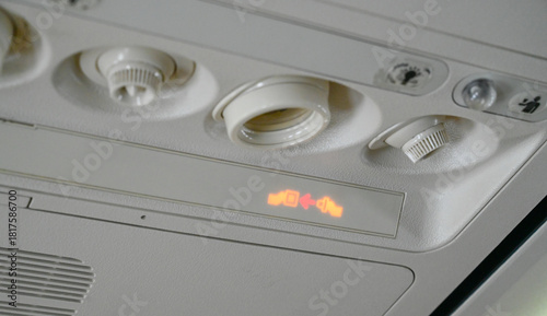The seat belt light on the plane is on. Warning passengers to fasten their seat belts during the flight. Illuminated seatbelt sign in an airplane. Airplane safety sign. 