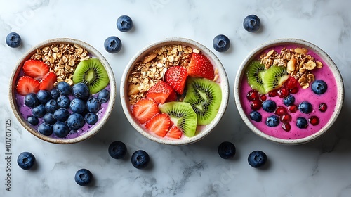 Delicious smoothie bowls topped with vibrant fruit and granola, perfect for a healthy breakfast or snack on a bright marble surface, a colorful and tasty treat