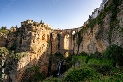 Historic Puente Nuevo bridge connecting the old and new parts of Ronda over El Tajo gorge with a waterfall in Pieblos Blancos of Andalusia, Spain