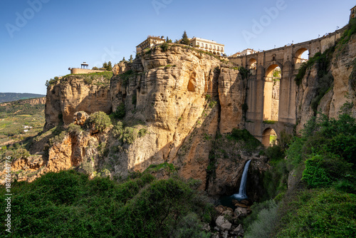Historic Puente Nuevo bridge connecting the old and new parts of Ronda over El Tajo gorge with a waterfall in Pieblos Blancos of Andalusia, Spain