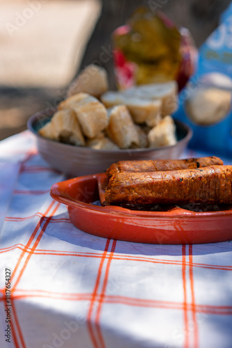 Portuguese flame grilled chorizo on a terracota grill with bread on the background