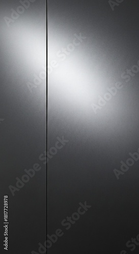 Two dark subtly textured metallic panels divided by a vertical line illuminated by a bright diagonal gradient light