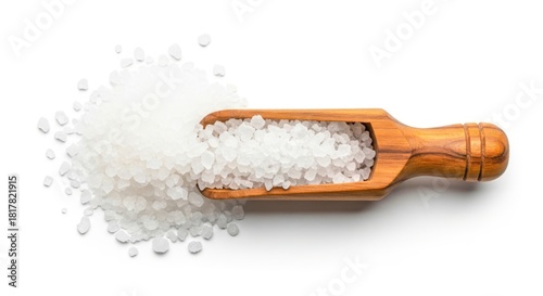 A wooden scoop filled with coarse sea salt and spilling onto a clean white background isolated on white background