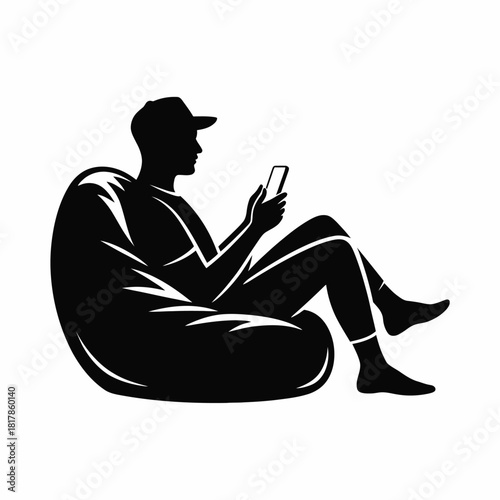 Person wearing cap sitting on beanbag using smartphone silhouette