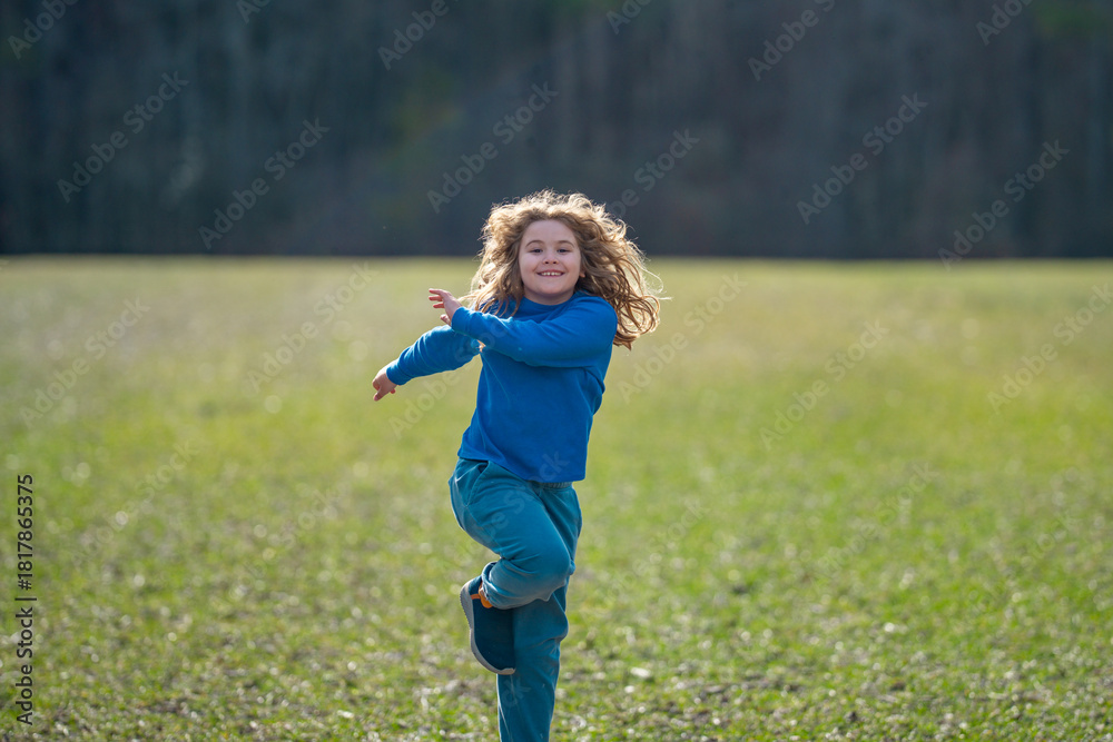 Fototapeta premium Child running on field. Happy kid running outdoors. Child jumping and running in nature. Kid running in a meadow. Summer fun for active child. Playful kid freedom. Carefree childhood in nature.
