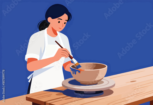 A woman in a white apron paints a ceramic bowl on a wooden table, blue background