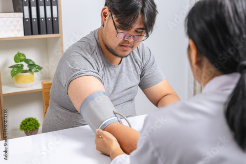 A female doctor measures an obese man's blood pressure.