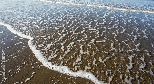 Fototapeta Naklejka Na Ścianę i Meble -  Ocean wave foam receding over wet sand at the beach shore