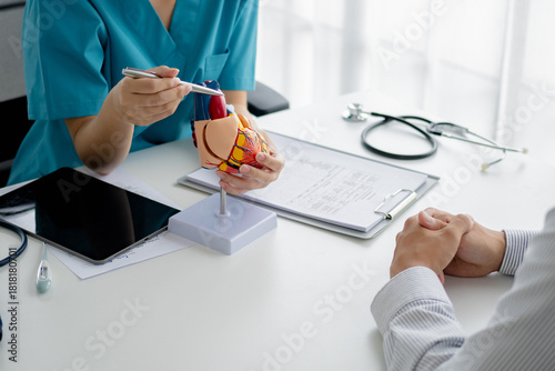 Photos cardiologist explain a heart model with a patient about heart disease in hospita