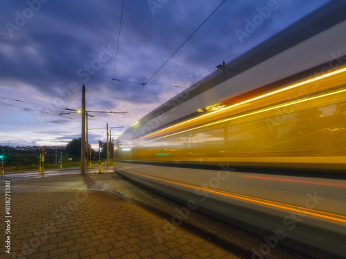 Tram stop. Public transport and sky during sunset. Blurred lights when the tr...