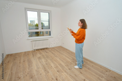 Принти на полотні Woman inspecting new apartment, making notes on clipboard