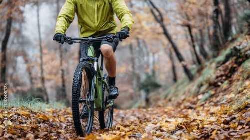 A cyclist dressed in bright chartreuse navigates a leaf-covered path in a serene forest during autumn