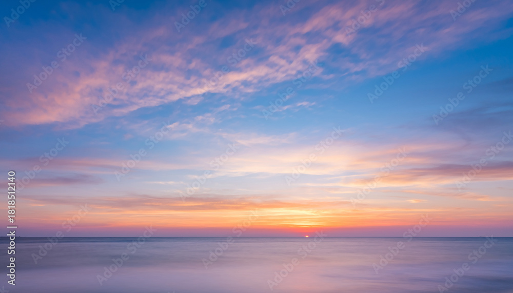 Obraz premium Ocean horizon at sunset with colorful clouds and calm water.