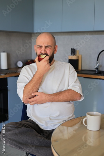 Obraz na plátne Man reacting strongly while biting into an apple, expressing an unpleasant or su