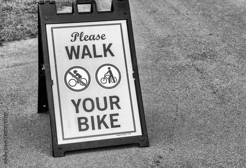 Scenic pathway with “Walk your bike” sign guiding cyclists through park or city walkway