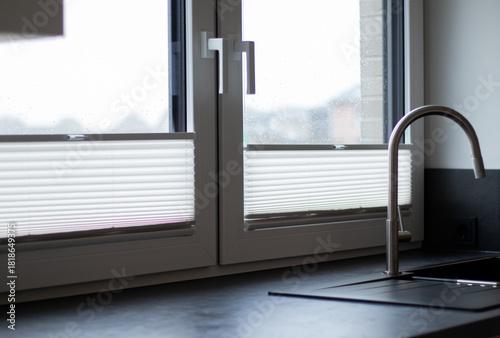White pleated blinds on two windows in the kitchen, cloudy daylight outside 