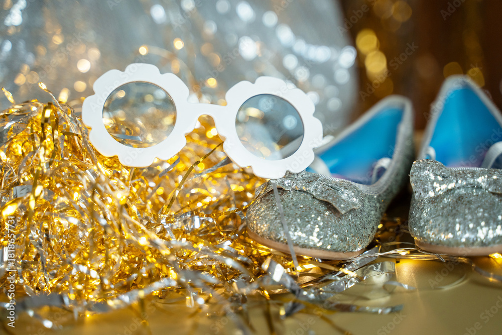 Shiny tinsel and glitter create a festive New Year atmosphere. Soft bokeh lights glow in gold and silver tones. Party props and accessories add a playful celebration mood.