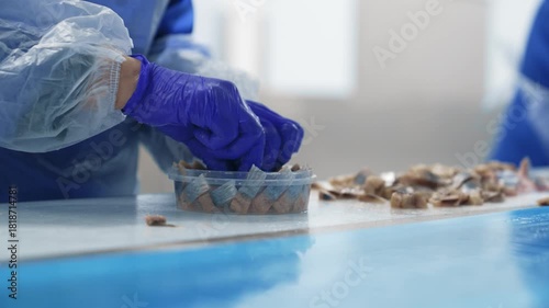 A worker places fish in a container for sale. Herring production.