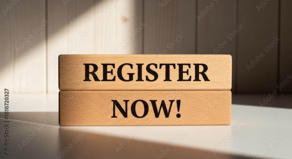 Obraz premium Register Now Wooden Blocks: Close-up of a wooden sign that reads Register Now! against the backdrop of a clean surface with sunlight casting long shadows. Encourages immediate action.