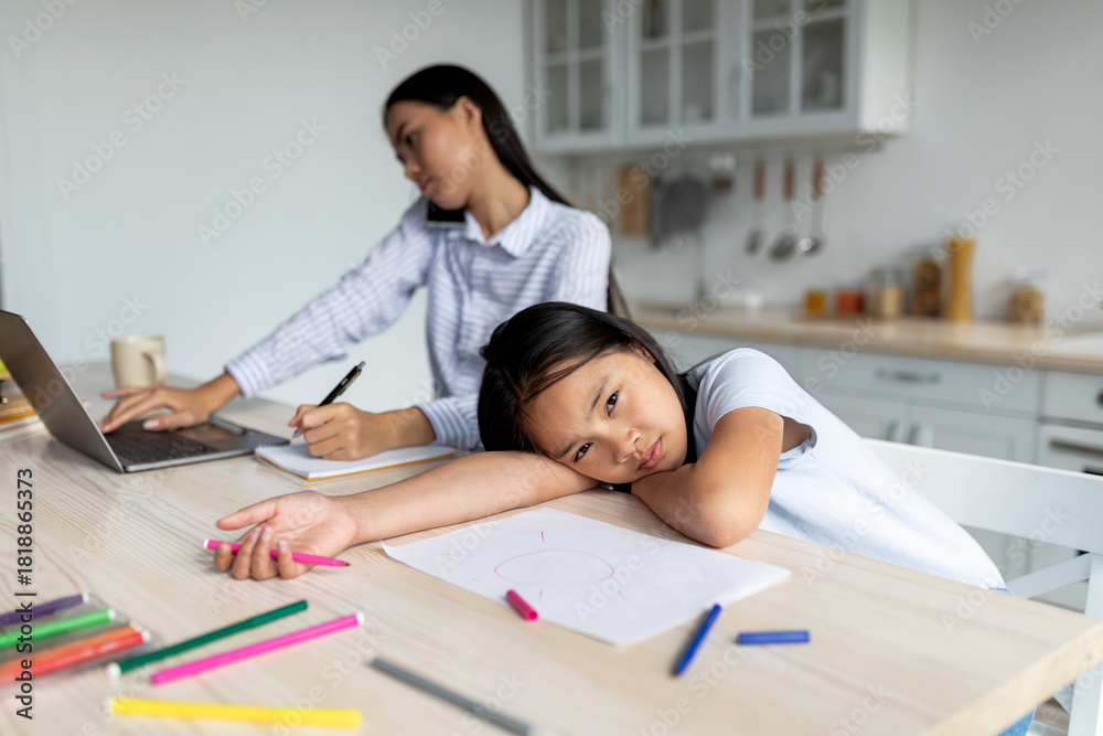 Φωτογραφία Young korean mother is busy working from home with her laptop, ignoring her little girl who feels offended and lonely