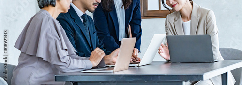 複数世代のビジネスパーソンが会議中に笑顔で話し合っているシーン。