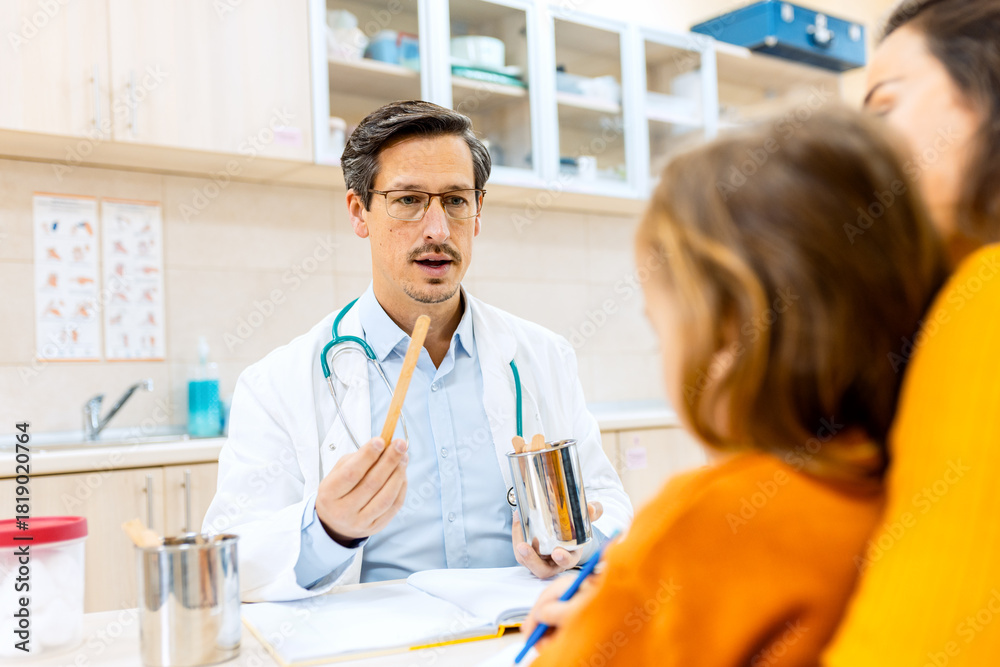 Obraz premium Male pediatrician consulting with a woman and her young child during a medical checkup in clinic.