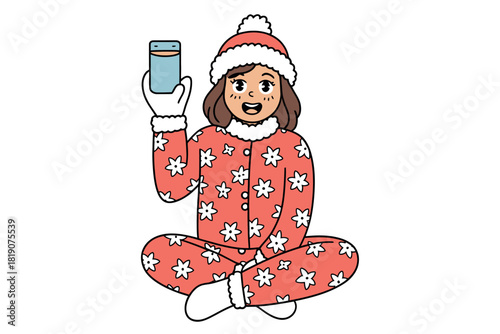 A happy person wearing a festive pajama set and winter hat holds up a mobile phone while sitting cross-legged on a white background.