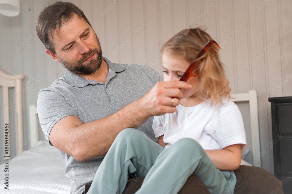 Obraz premium Man brushing daughters hair. Daddy combing girl's hair at home. Responsible good dad braiding his child girl's hair. Handsome father grooming his little one. Morning routine concept. Family life