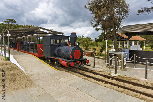Small tourist train departing from Santa Luzia, Portugal, crossing salt marshes and dunes toward Praia do Barril,