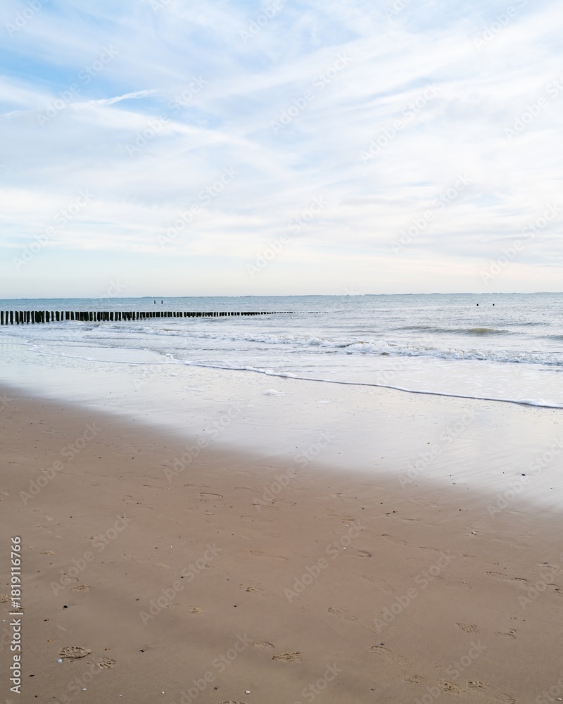 Fototapeta premium lonely beach with waves and sky in zeeland, the netherlands