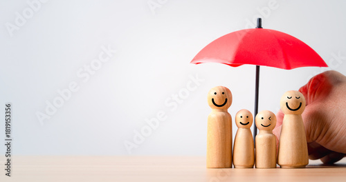 Fotografie Wooden family figures under a red umbrella representing insurance protection saf