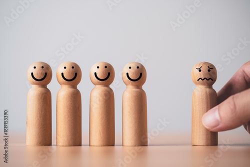 Schilderij op canvas Wooden figures with happy faces standing together while one sad figure is being