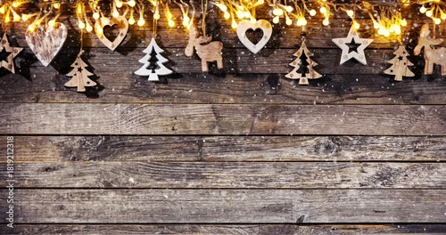 Cozy Christmas decorations arranged on rustic wood with gentle falling snow creating a festive winter atmosphere. Ideal as a holiday background or seasonal backdrop.
