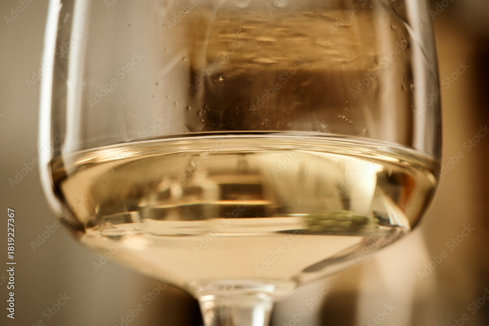 Naklejka premium Close up showing glass of wine with liquid, surface reflecting surroundings, highlighting clarity and color of beverage during wine tasting session, no people visible