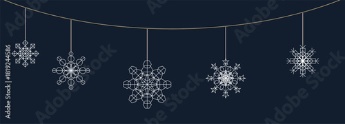 Decorative snowflakes hanging on a string against a dark background during winter festive season